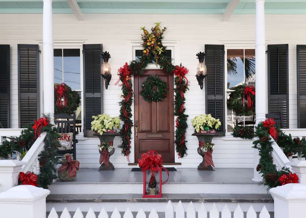 The front porch of a Key West home is decorated with red bows and wreaths, making them ready for Key West in December!