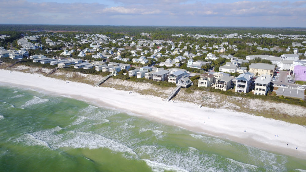 a row of houses along the beach with white sand and emerald water