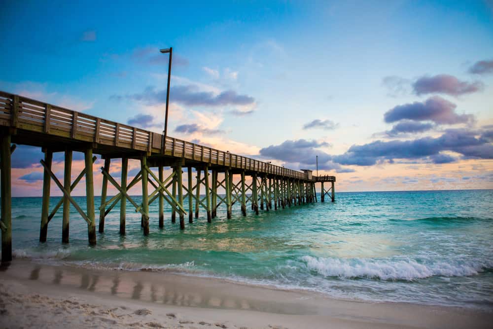 wooden pier extending into emerald water on beach