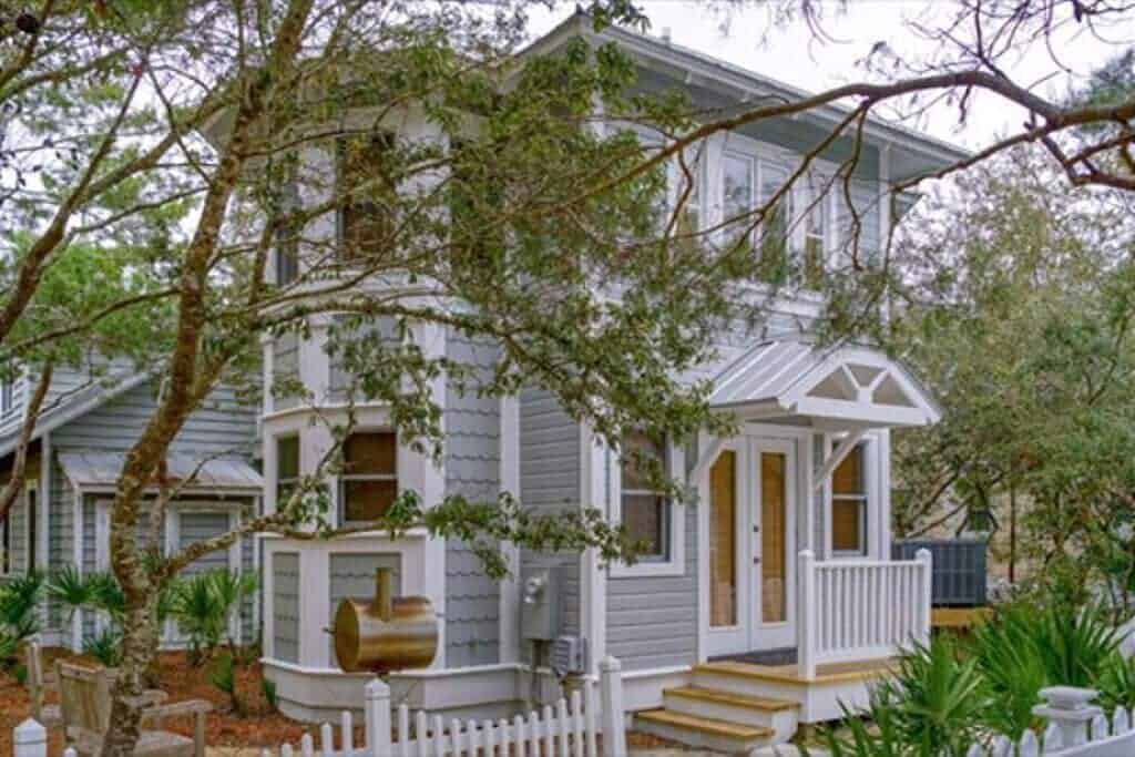 A grey rental cottage surrounded by trees