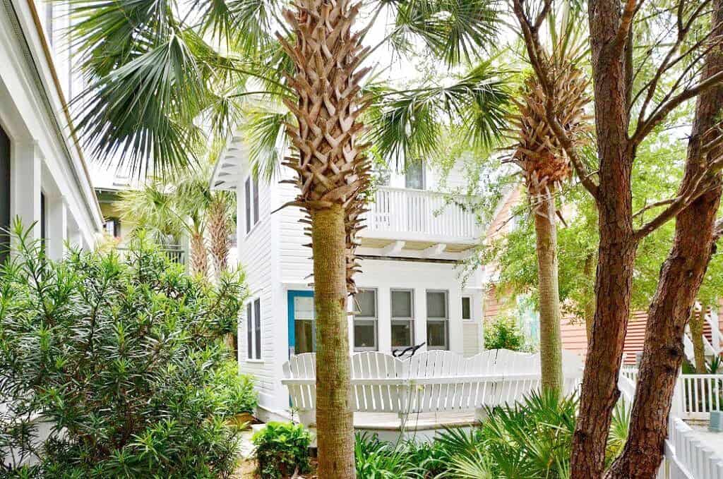 Tress in the foreground and a white beach house in the background