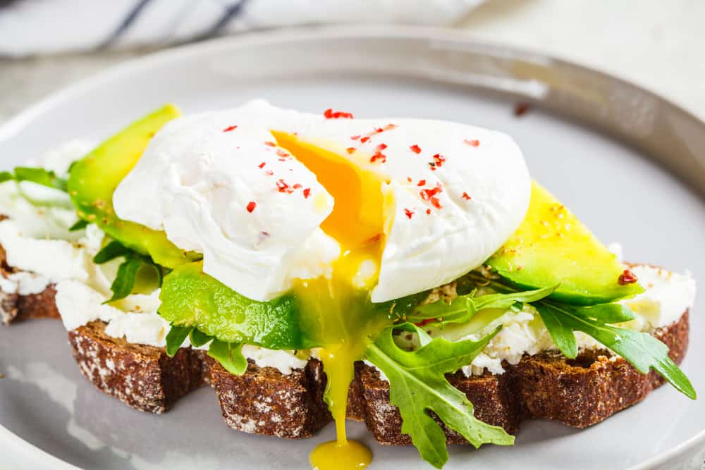 Avocado toast with arugula and a poached egg, similar to avocado toast you can order for breakfast in Naples.