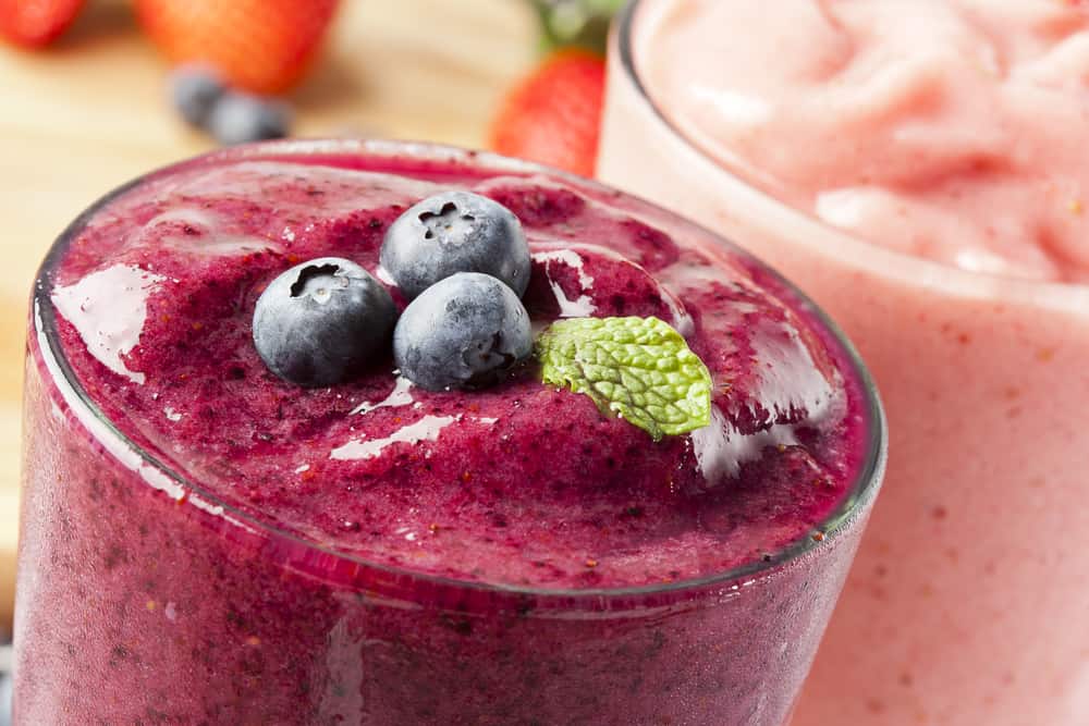 Three blueberries sit as garnish on a berry smoothie, similar to one you can order from Cafe Nutrients for breakfast in Naples.