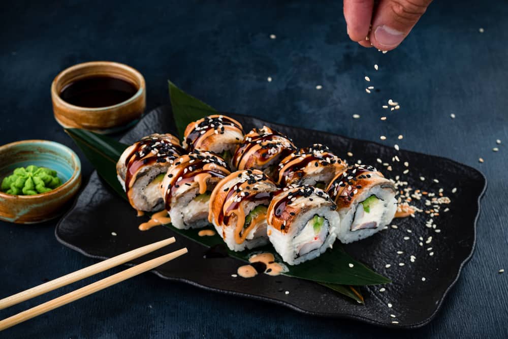 Sprinkling sesame seeds on a sushi roll at one of the best restaurants in Miami for sushi, Moshi Moshi. 