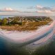 An aerial photo of the somewhat secret beach that is one of the best things to do in Anna Maria Island. The beach is at the very end of the island and in the distance you can see a town.