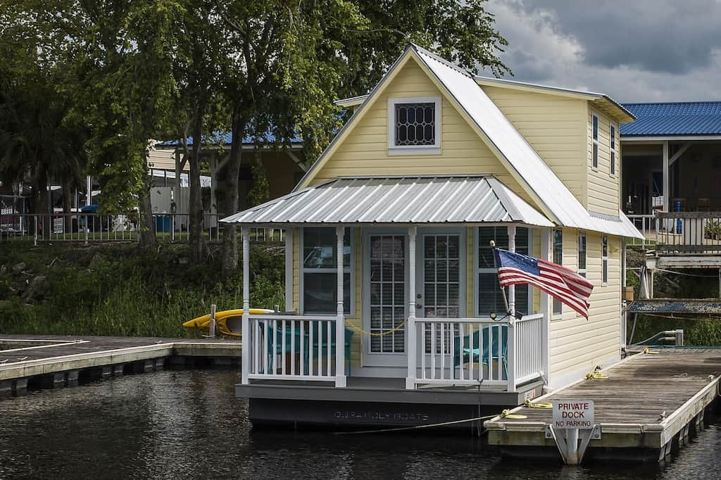 View of the cheery butter yellow cabin with aluminum roof floating on the river. 