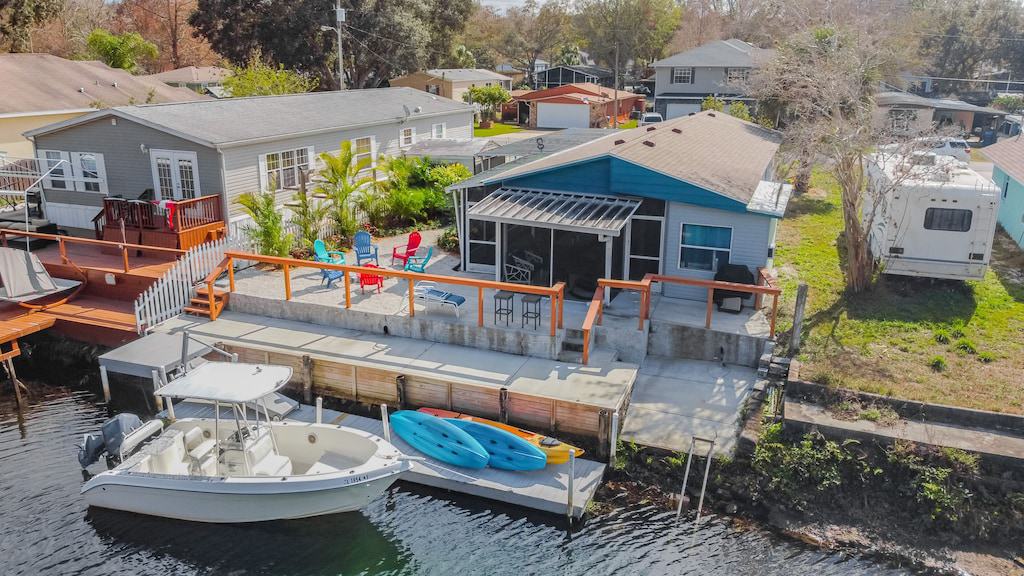 Aerial photo of the beautiful canal house. It has a large screen porch with kayaks outside and a large dock. This is one of the best glamping spots in Florida.