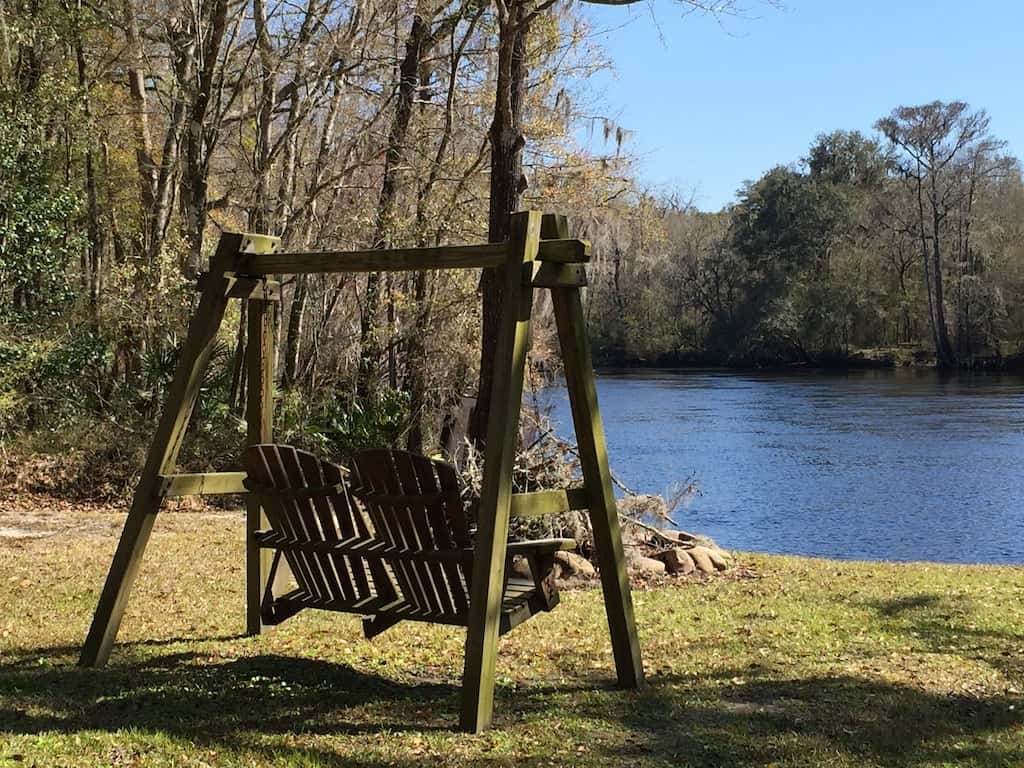 Cute porch swing overlooking the river at Lazy Turtle Lodge, one of the best glamping spots in Florida. 