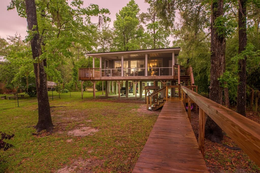 Walk alongside the long wooden dock to this two level gorgeous wooden treehouse with an entire wall of windows
