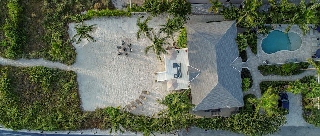 An aerial view of this luxury property that includes the pool, the expertly landscaped tropical grounds, and the sandy path to the beach. 