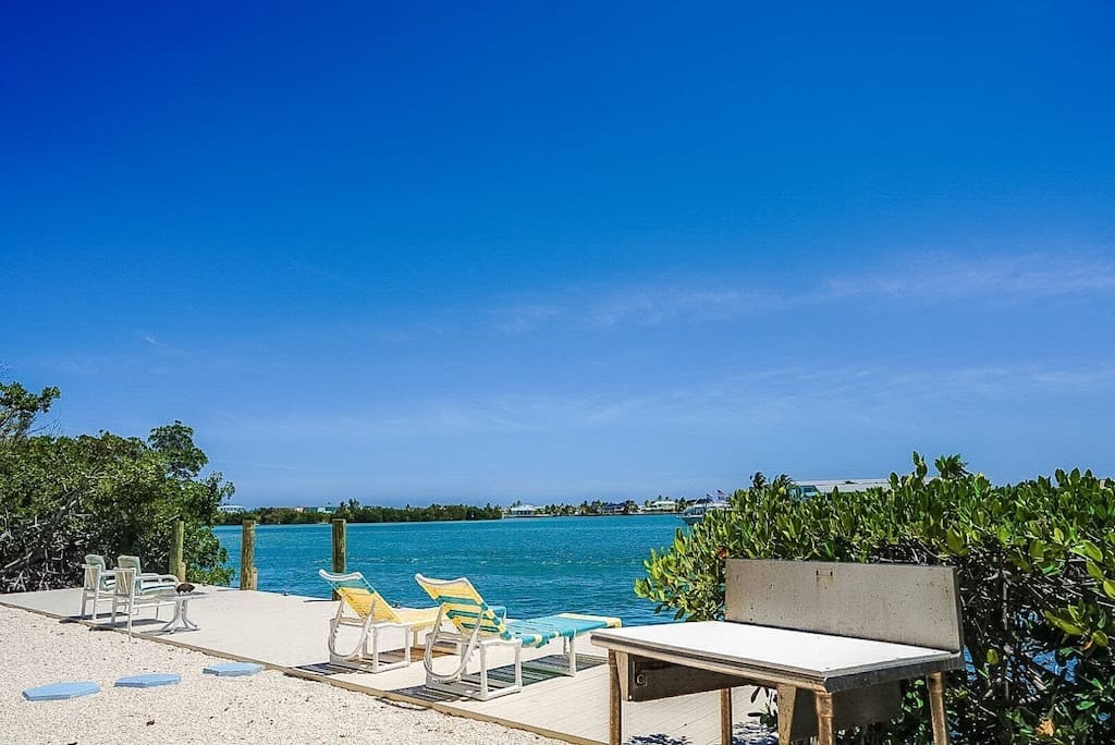 View of the strikingly teal blue water near Fins to the Left. Two inviting reclining pool chairs sit and take in the view. 