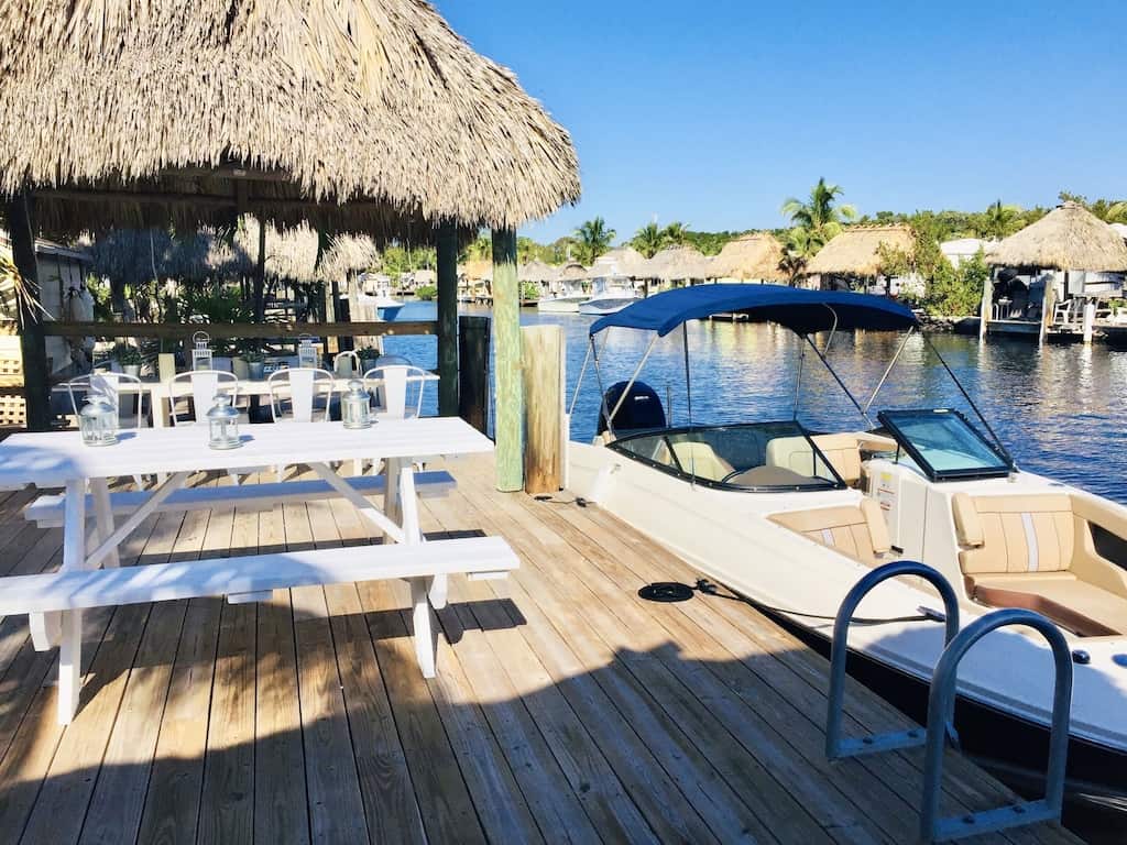 View of a docked speedboat at a doc with lovely outdoor dining gazebo at the Waterfront Tiny House, one of the best Airbnbs in the Florida Keys. 