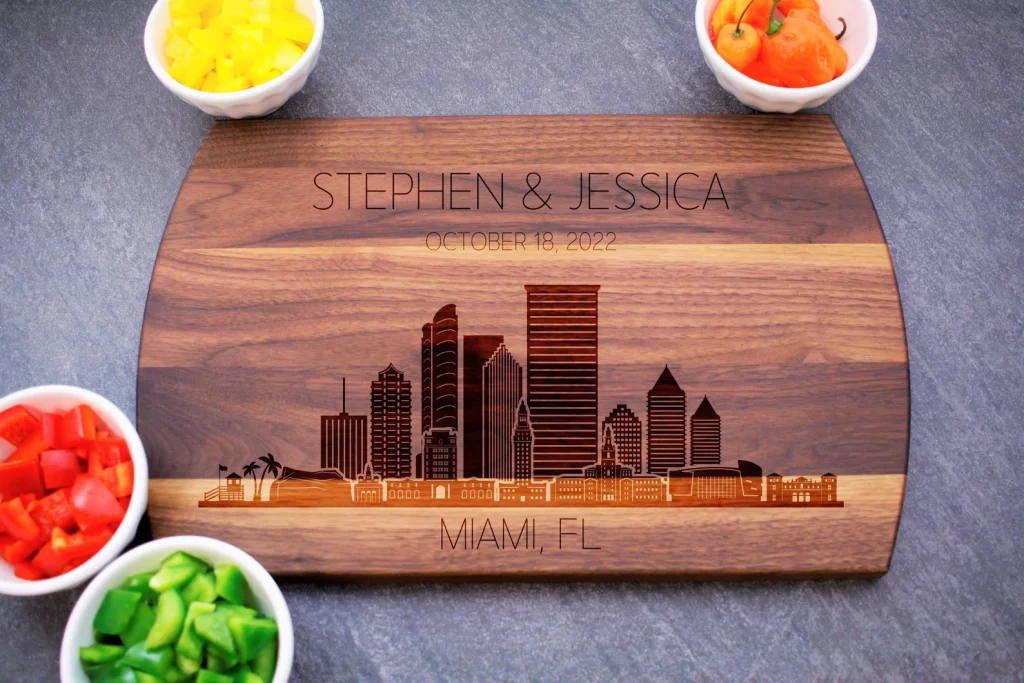 a picture of a personalized cutting board with the Miami Skyline, a date, and two names. A perfect Miami gift!