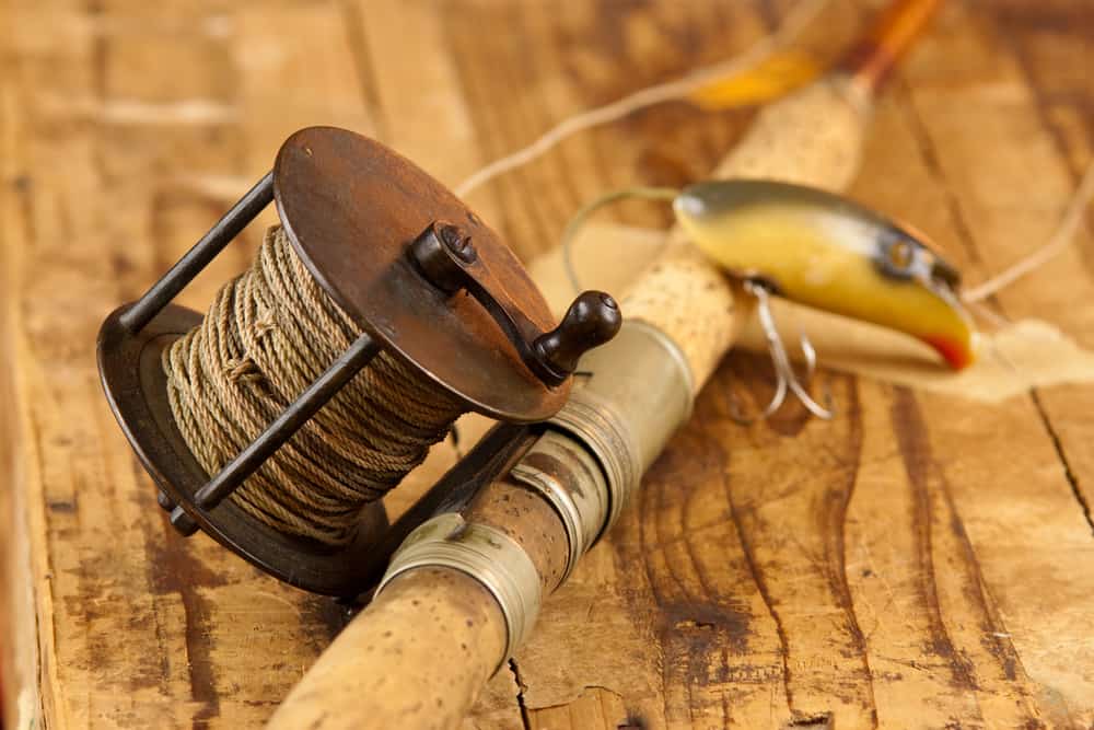 Detail photo of an old fishing reel on a rod with a lure.