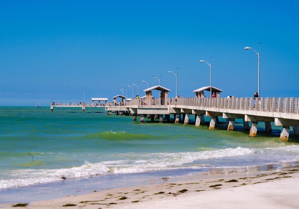 The fishing pier at Fort De Soto Beach stretching into the water on a clear day.