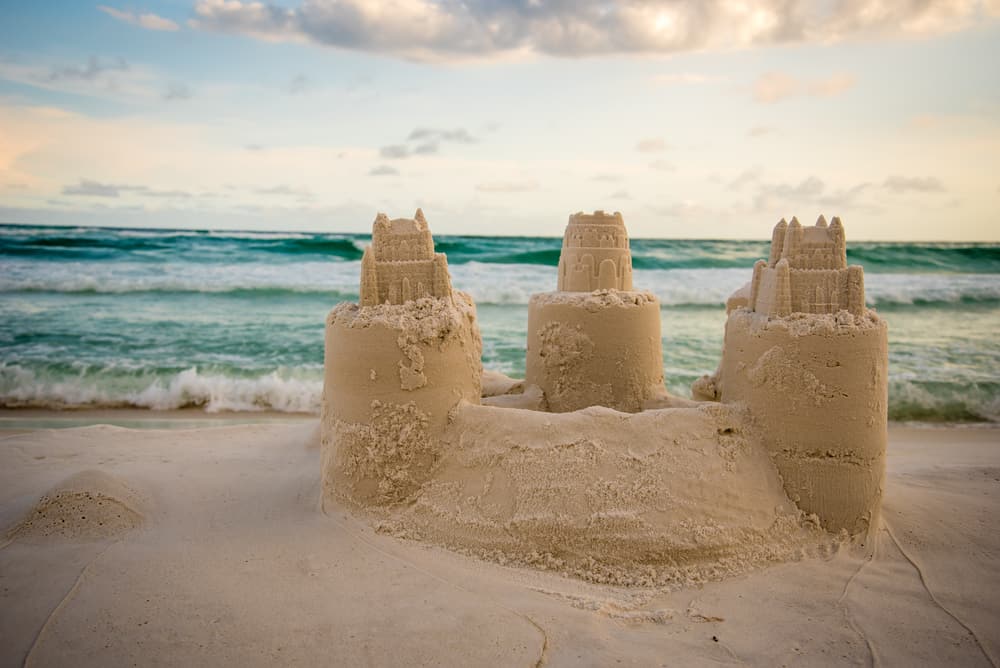 Pretty sandcastle with the sunset over the ocean behind it.