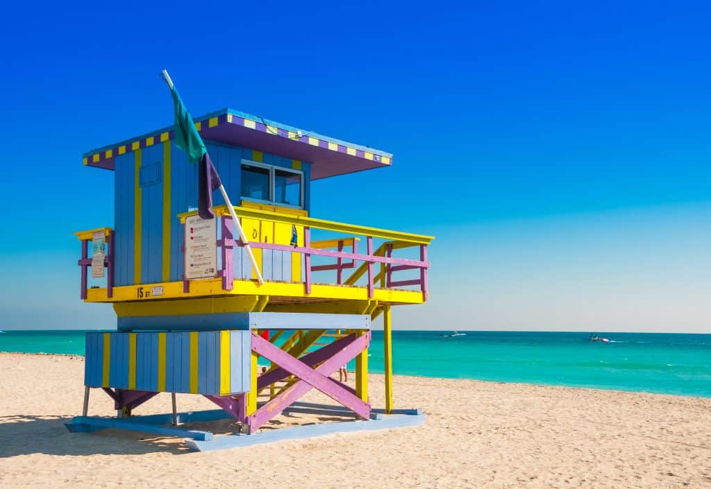 A colorfully painted lifeguard station on Miami Beach. The station is periwinkle, grape purple, teal, and yellow