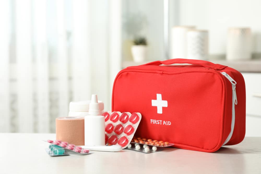 A red first aid bag with pills, bottles, and more, an essential for a Florida packing list.