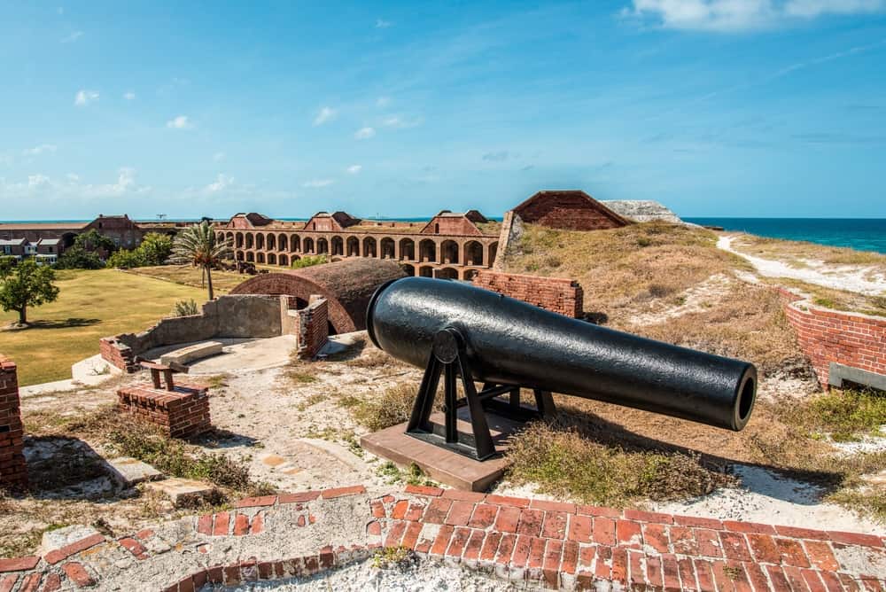 A historic cannon sitting atop the out wall of Fort Jefferson with views down to the interior.