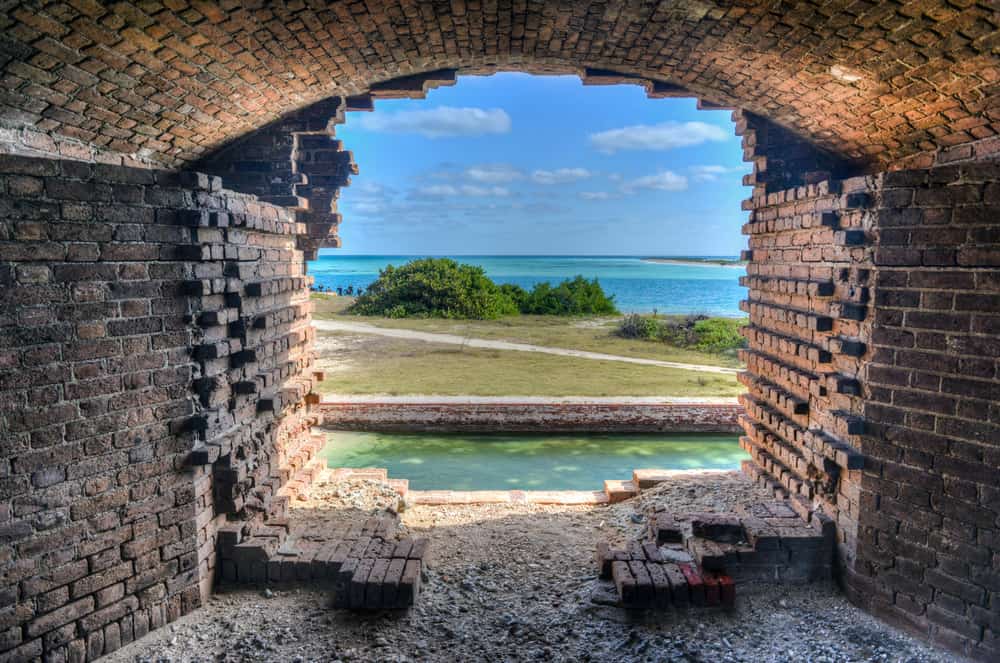 Looking out of an old, brick window at Fort Jefferson towards the nature of the park and the ocean.