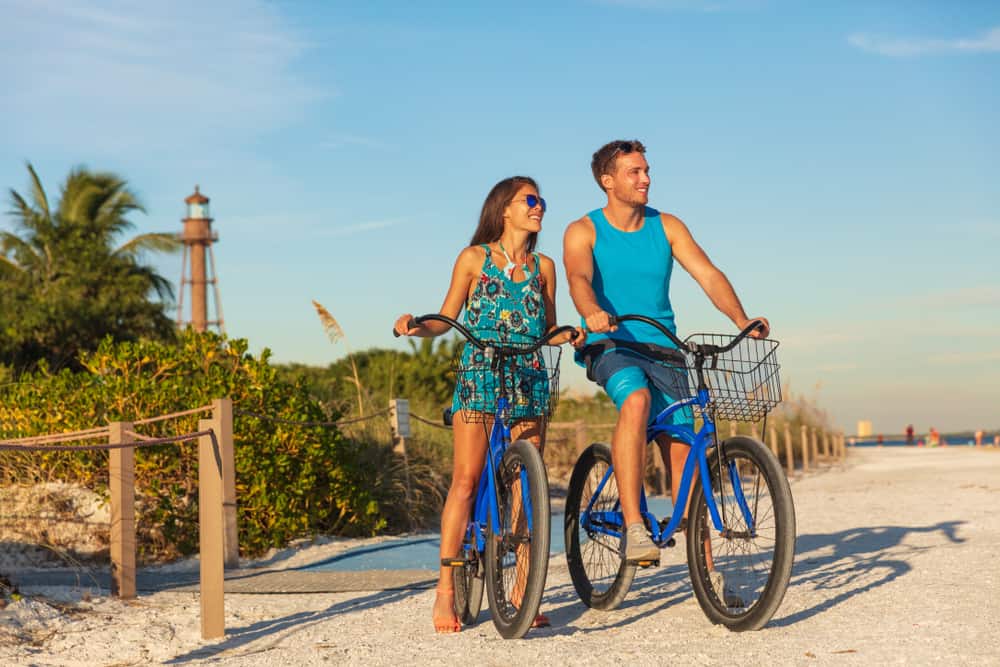 Man and woman sitting on blue bikes on a beach in Florida.