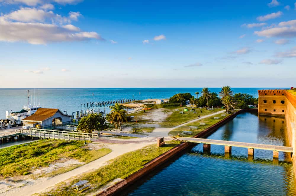 View looking down at the dock and entrance to Fort Jefferson with campsites in the distance and the ocean at golden hour.