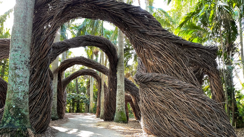 Wooden archways made of entwined branches stand over a walkway at McKee Botanical Gardens, one of the best things to do in Vero Beach.