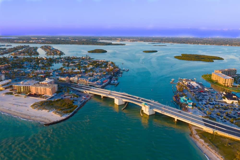 An Ariel view of Maderia beach and the Johns Pass bridge and boardwalk area overlooking the water and white sand beaches 