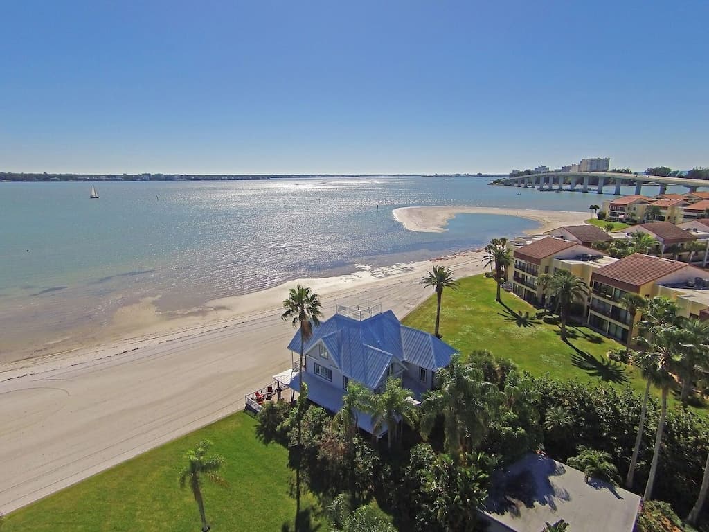 Aerial view of the home surrounded by palm trees and located on a private beach. 