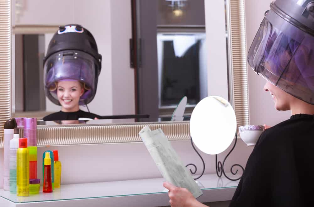 A woman at a salon, demonstrating one of the weird laws in Florida, falling alseep under a hairdryer. 