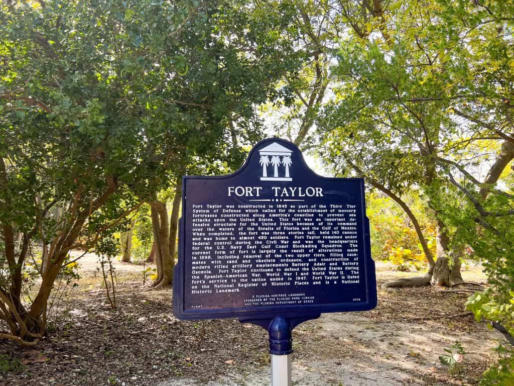 A Florida Historic Landmark sign, surrounded by trees, giving a brief history of Fort Zachary Taylor when it was a military fort.