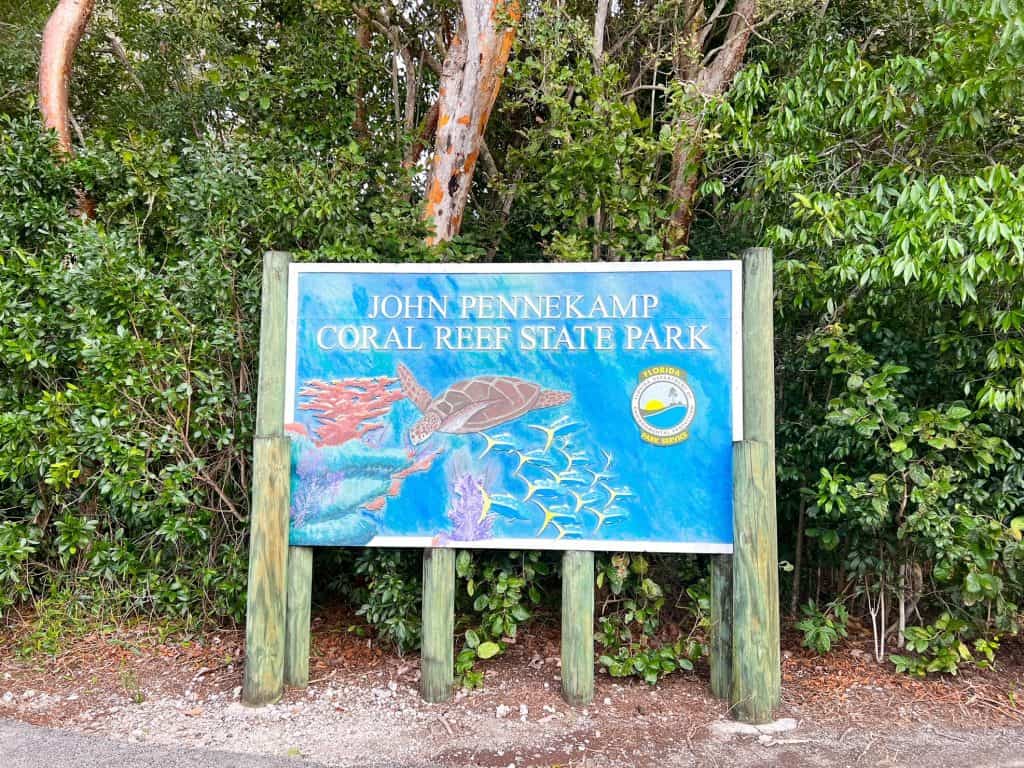 Sign for John Pennekamp Coral Reef State Park showing a painting of a reef with a turtle and fish.