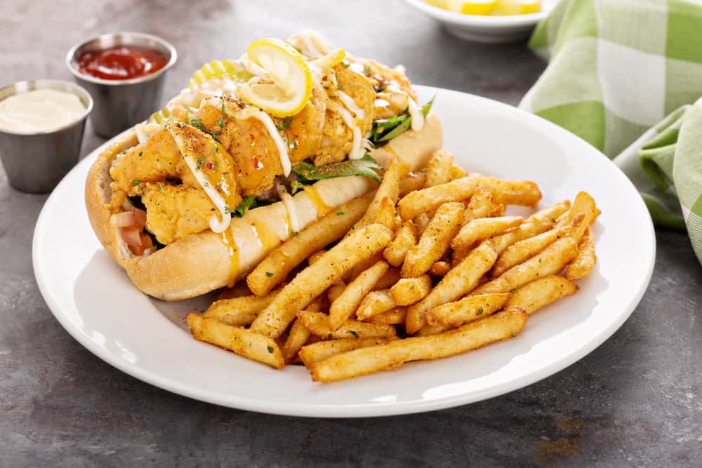 A shrimp po’boy sandwich with a side of fries.