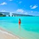 Victoria faces and walks toward Old Bahia Bridge in a red bathing suit, wading in the clear blue water at Bahia Honda State Park.
