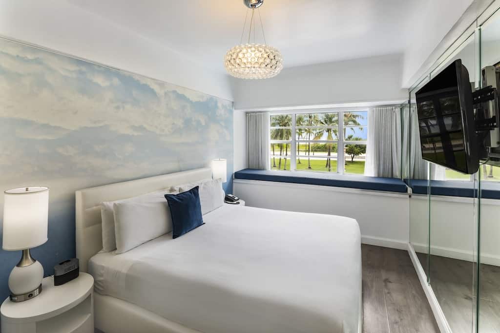 View of the king sized white bed, wall mural, and view of the ocean from this Penguin Hotel Suite. 