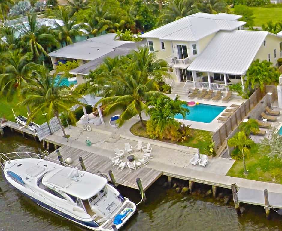 Aerial view of the Luxury Villa with the palm trees, pool, firepit,  balconies and optional yacht on full display. 