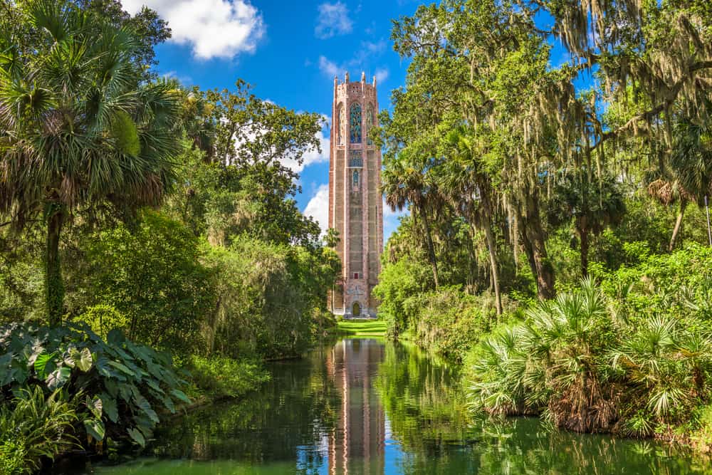 Tok Tower is a tall brick building surrounded by trees and a pond that reflects the tower