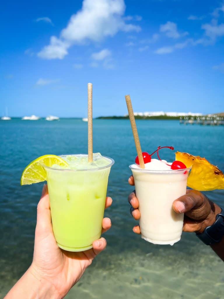 a couple posing with two frozen drinks overlooking the ocean 