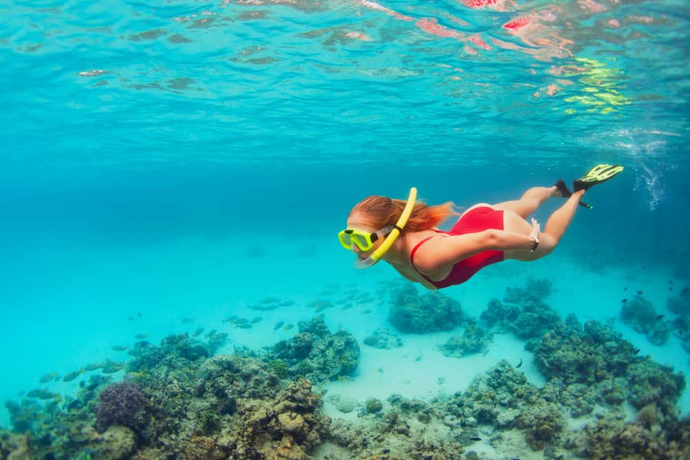 a girl in a red swimsuit is snorkeling