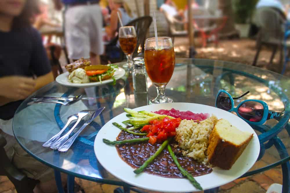 a.n outdoor table with tea to drink and a plate of rice and beans 