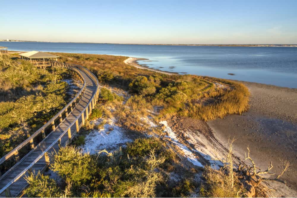 A wooden boardwalk curves along the shore, cutting over dunes and vegetation on Perdido Key, which has some of the best Panhandle beaches