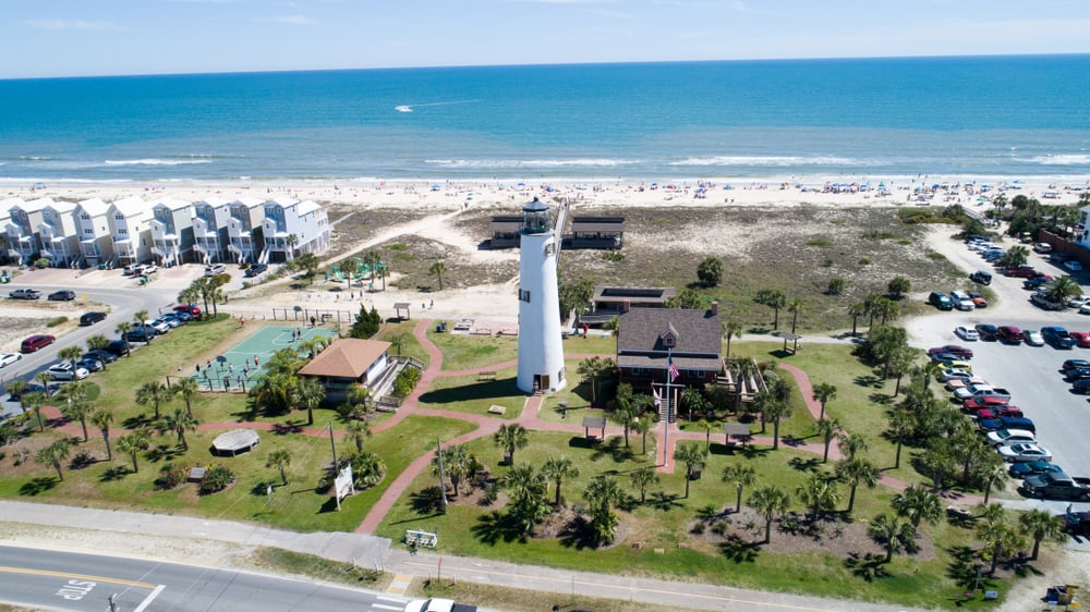 An aerial shot of the St. George Island and surrounding palm trees, parking lots, and beach houses that sit on the shore of one of the best Panhandle beaches.