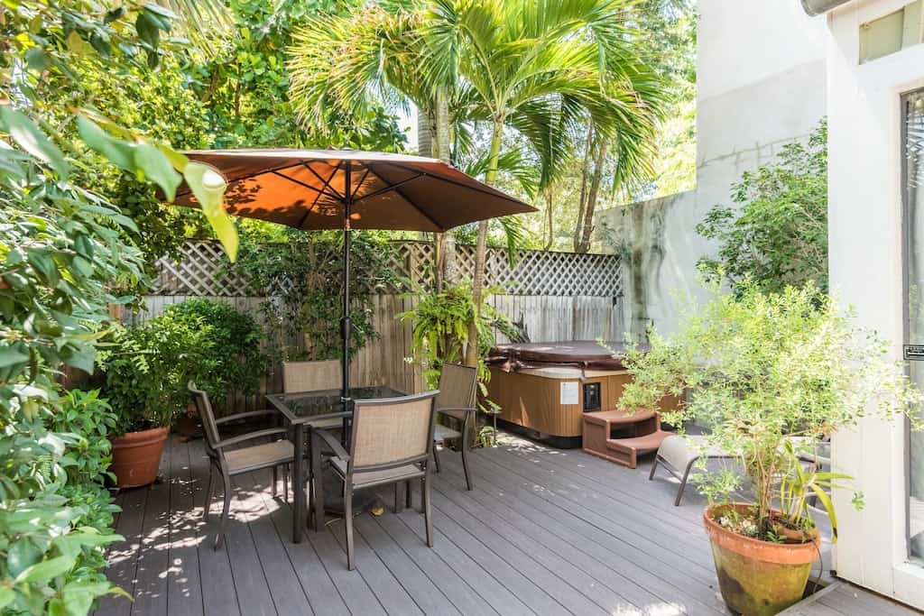 View of the deck, lush backyard, and private hot tub of the Conch Cottage. 