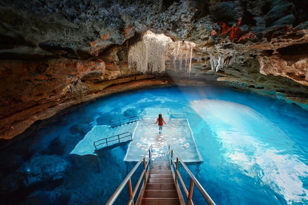 A woman takes in the views at Devi's Den as she stands on the stair's platform under the vastness of the ancient cave. 