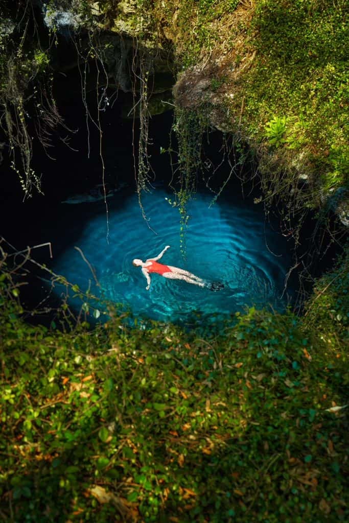 The chimney perspective once again shows a woman floating on her back at Devil's Den. The green moss that dangles from the hole frames her floating figure. 