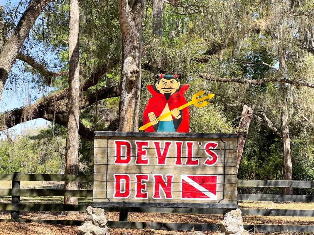 The sign for Devil's Den is hard to miss: it features a Devil, the name of the location, and a scuba flag.