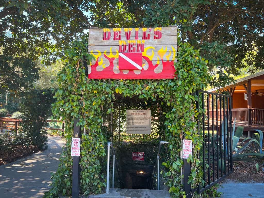 On the entrance to the stairs that descend into Devil's Den, there is a sign that features the name as well as flames. The stairs themselves are covered with greenery and the rules of the location.