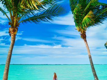 photo of woman standing in palm trees at one of the best islands in the florida keys