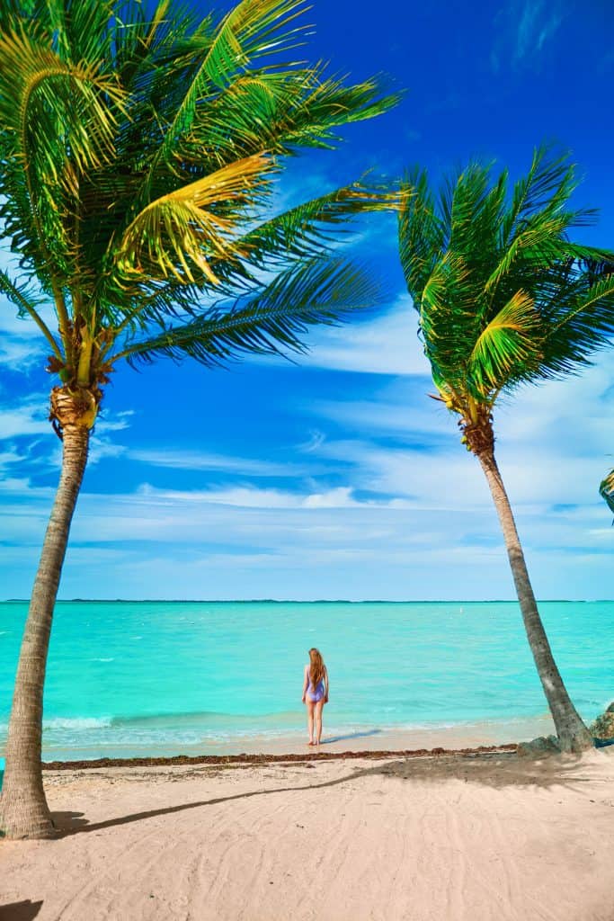 photo of woman standing in palm trees at one of the best islands in the florida keys