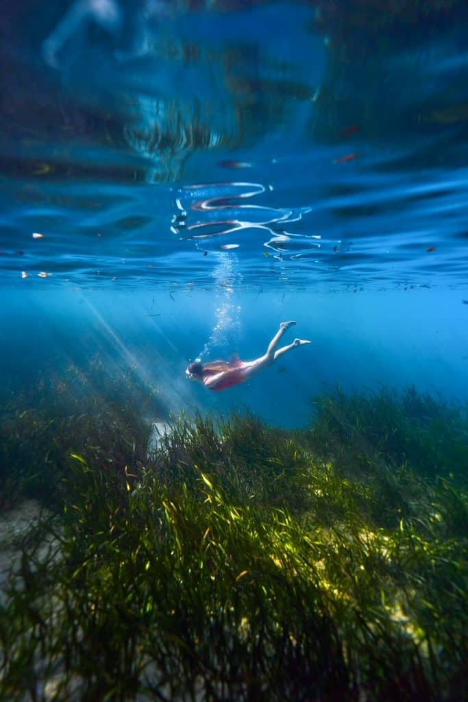 A woman dives deep under the water at Juniper Springs with a snorkel mask.